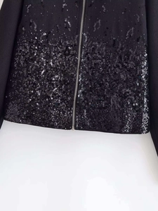 Detail shot of shimmering black sequins and silver metal zipper on a classic autumn jacket