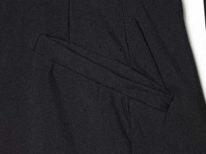 Macro shot of black fabric texture and pocket detail on a V-neck jumpsuit