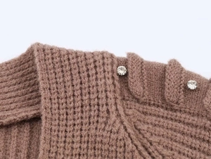 Close-up of brown knit sweater texture featuring shimmering rhinestone buttons on shoulder