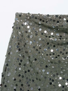 Détail des paillettes noires et argentées ondulées sur le tissu de la jupe vert olive