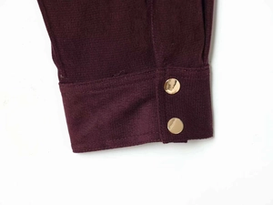 Detail of burgundy ribbed sleeve cuffs with decorative polished gold round buttons