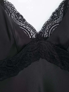 Détail du col en V avec bordure en dentelle noire délicate sur tissu en satin soyeux