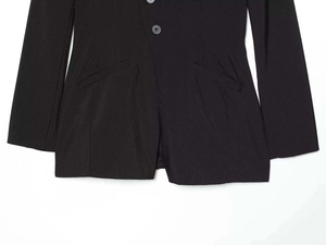 Detail of black V-neck romper featuring a double-button closure and symmetrical slanted pockets