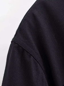 Close-up of black twill fabric texture and professional shoulder stitching on the jacket
