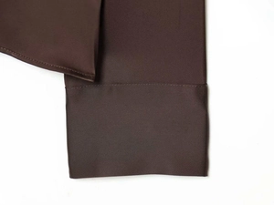 Detail view of smooth dark brown satin fabric texture and premium stitching on shirt cuff