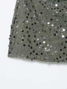 Gros plan des paillettes gris foncé à motif tourbillon sur une mini-robe vert olive