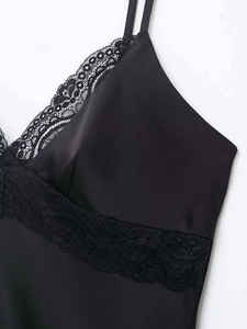 Détail du caraco en satin noir avec bordure en dentelle florale et décolleté en V