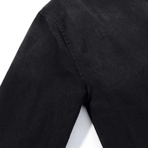 Close-up of shoulder seam stitching on black denim jacket with twill texture