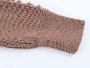 Macro shot of brown chunky knit cardigan showing ribbed cuffs and button detailing