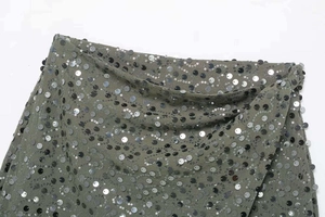 Détail de paillettes argentées sur tissu vert armée avec coutures fines pour minijupe