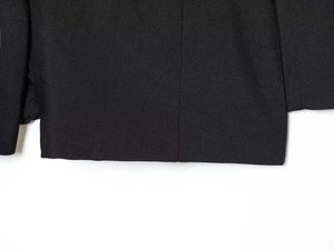 Detailed macro view of the black twill fabric texture and stitching on the hem of a jumpsuit