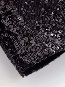 Detailed macro view of black sequin embellishments on a premium textured fabric jacket