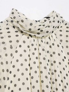 Close-up of retro polka dot chiffon blouse featuring a pleated high neck and soft texture