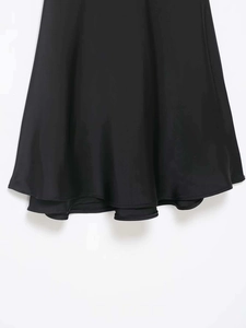 Vue macro détaillée de l'ourlet de la robe en satin noir montrant une couture fine