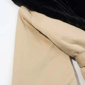 Dettaglio di un cappotto in cotone kaki con collo in ecopelliccia nera e cuciture sulle spalle