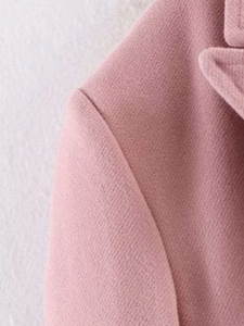 Detailed close-up of pink wool coat shoulder seam with premium twill texture and stitching