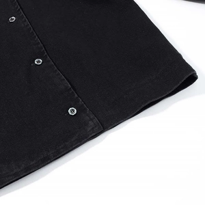 Asymmetrical black denim jacket hem with detailed metal buttons and twill fabric texture