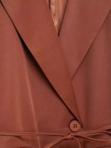 Detailed macro view of the rust brown blazer featuring classic lapel and waist tie detail