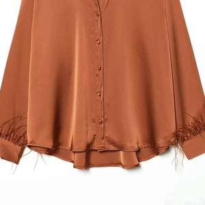 Elegant satin blouse in caramel brown featuring feather cuffs and covered buttons detail