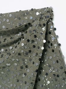 Détail de près d'un tissu vert armée avec broderie complexe de paillettes argentées