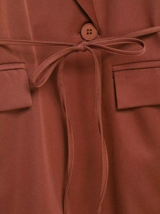 Detailed macro view of the caramel brown suit waist with button and ribbon tie details