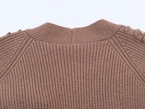 Detail of brown ribbed knit cardigan featuring rhinestone embellishments on shoulder seam