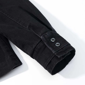 Detail of black denim jacket sleeve featuring dual button closure and twill texture