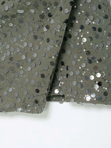 Détail du tissu vert olive avec broderie de paillettes complexes en motif de tourbillon
