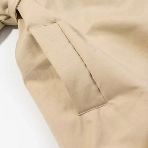 Dettaglio ravvicinato della tasca e delle cuciture su un cappotto imbottito beige
