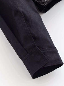 Macro detail of black jacket sleeve with decorative sequins and quality twill fabric