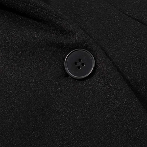 Macro shot of a black four-hole resin button on thick wool-like textured fabric coat