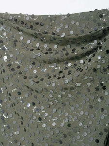 Vue macro du tissu à paillettes vert olive avec motifs de vagues en spirale brodés