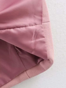 Close-up of pink wool coat hem showing textured tweed fabric and silky smooth lining