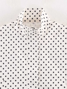 Close-up of white polka dot jacket with stand collar, zipper detail and S size label