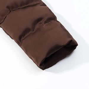 Gros plan détaillé du poignet de la doudoune marron montrant le matelassage et le tissu