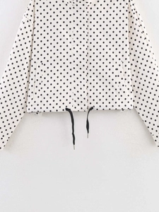 Close-up of white polka dot jacket featuring adjustable black drawstrings and side pockets