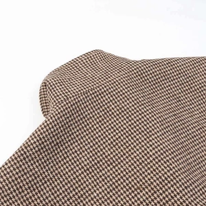 Detailed macro view showing the brown houndstooth textured fabric of the jacket
