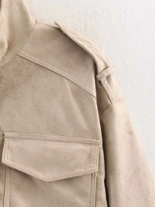 Detailed close-up of the shoulder epaulette and pocket flap on the beige suede jacket