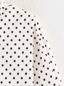 Detail of dropped shoulder seam and black polka dot pattern on cream long sleeve jacket
