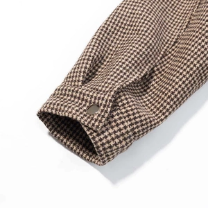 Close-up of vintage houndstooth jacket cuff with golden metal button detail
