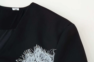 Detail of black dress with white eyelash lace trim on shoulder and neck area
