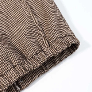 Detailed macro view of the houndstooth jacket featuring a metal zipper and silver snap button