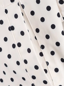 Close-up of white fabric with black polka dots featuring high-quality stitching detail