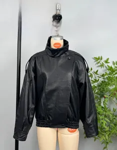 Detail of black faux leather biker jacket featuring high collar and snap button closure