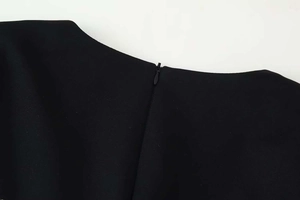 Detailed close-up of a hidden zipper on the back of a black lace dress with woven fabric