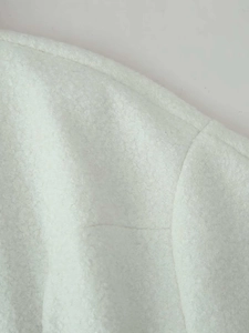 Close-up of white fleece coat shoulder seams showing soft plush texture and sewing detail