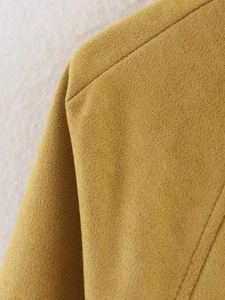 Macro del tessuto scamosciato giallo senape e delle cuciture raffinate sulla spalla della giacca
