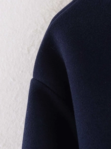 Macro detail of navy wool coat fabric showing premium texture and neat shoulder stitching