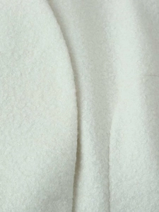 Close-up of cream white wool texture and thick fiber detail on autumn coat fabric