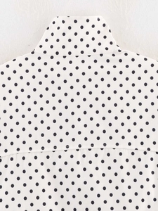 Detailed view of white polka dot blouse featuring high collar and reinforced back stitching